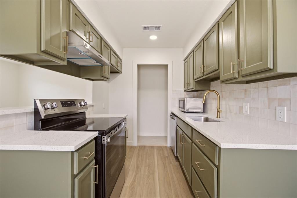 908 Isbell Road, Unit A Fort Worth, TX 76114 - Photo 4 of 28 Galley kitchen featuring sage green cabinetry, light-toned countertops, and wood-finish flooring
