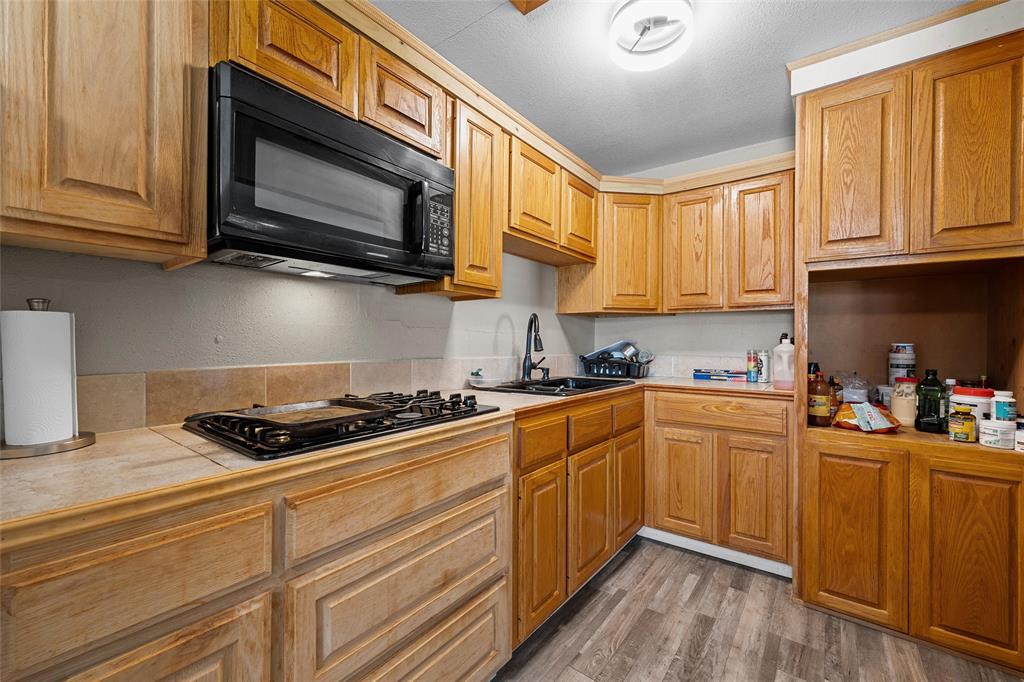 979 Old Mexia Road Waco, TX 76705 - Photo 8 of 40 a kitchen with stainless steel appliances granite countertop a stove a sink dishwasher and a microwave oven with wooden cabinets