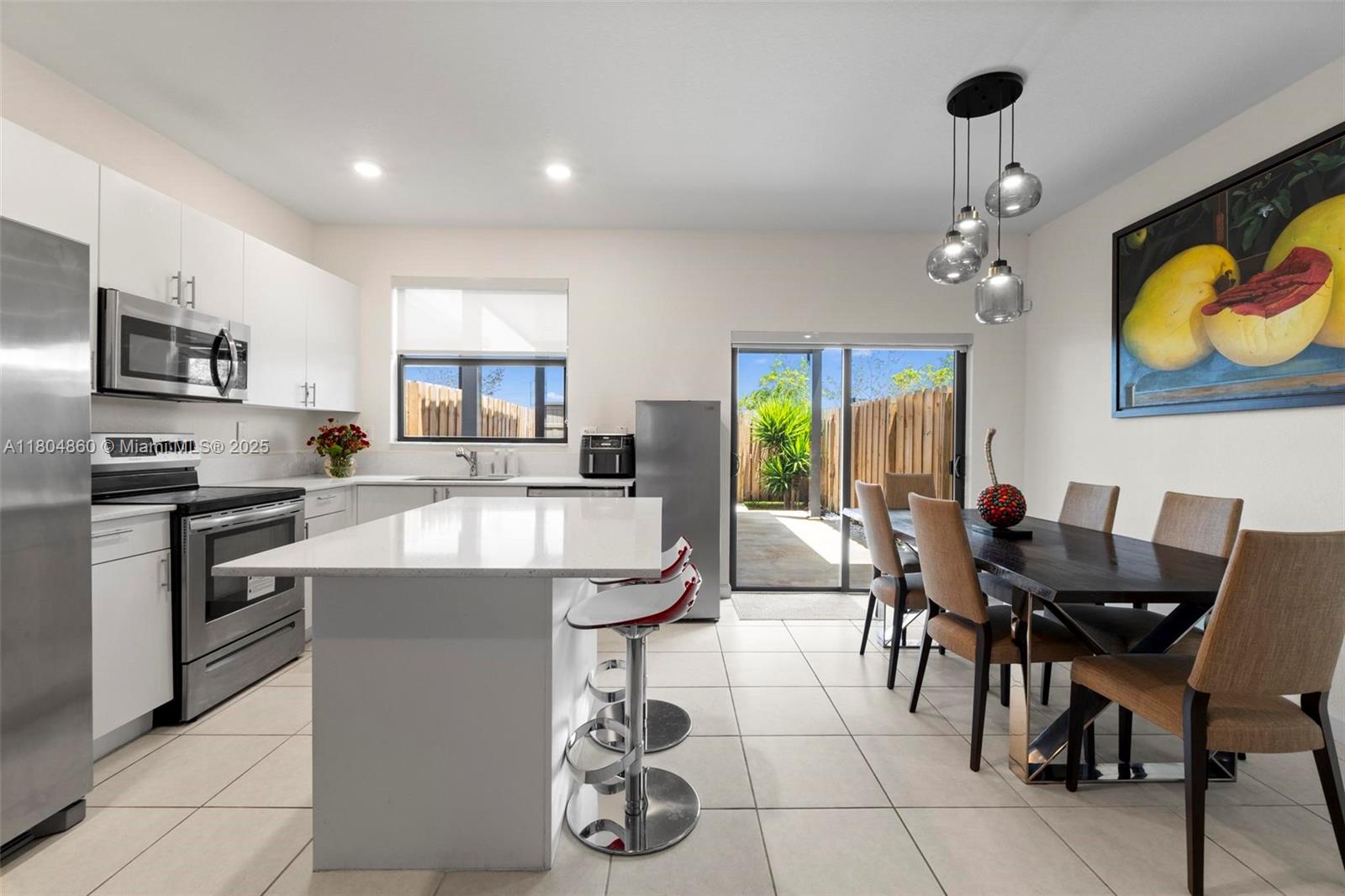 23517 Southwest 127th Place Homestead, FL 33032 - Photo 6 of 28 a kitchen with stainless steel appliances granite countertop a stove a refrigerator a kitchen island a dining table and chairs with wooden floor