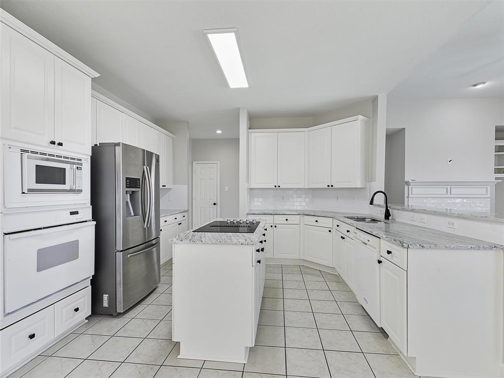 7612 Pendleton Street Dallas, TX 75252 - Photo 18 of 38 a kitchen with a refrigerator sink and cabinets