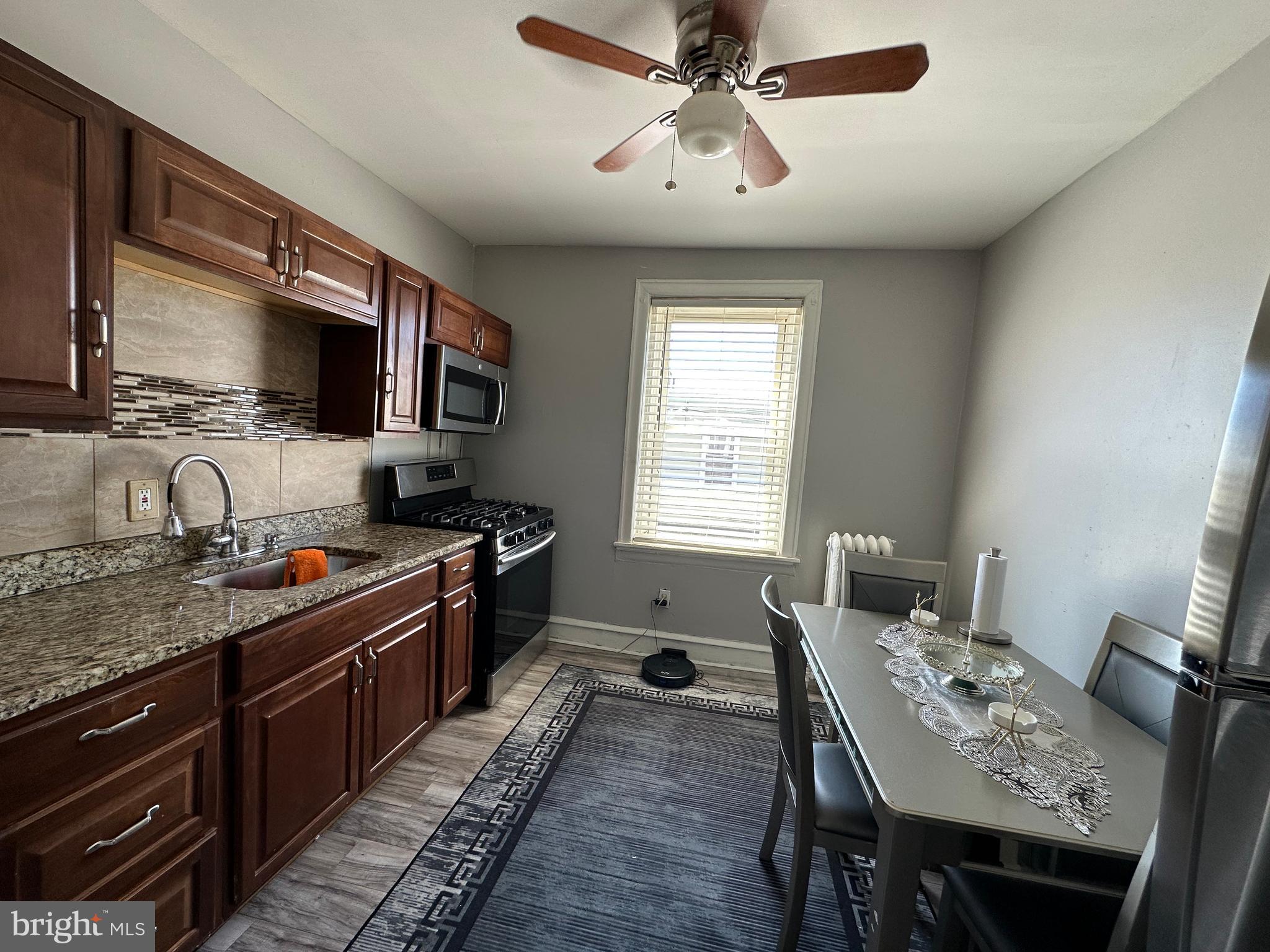 4914 Ormes Street Philadelphia, PA 19120 - Photo 27 of 33 a kitchen with stainless steel appliances granite countertop a stove top oven a sink dishwasher a dining table and chairs with wooden floor