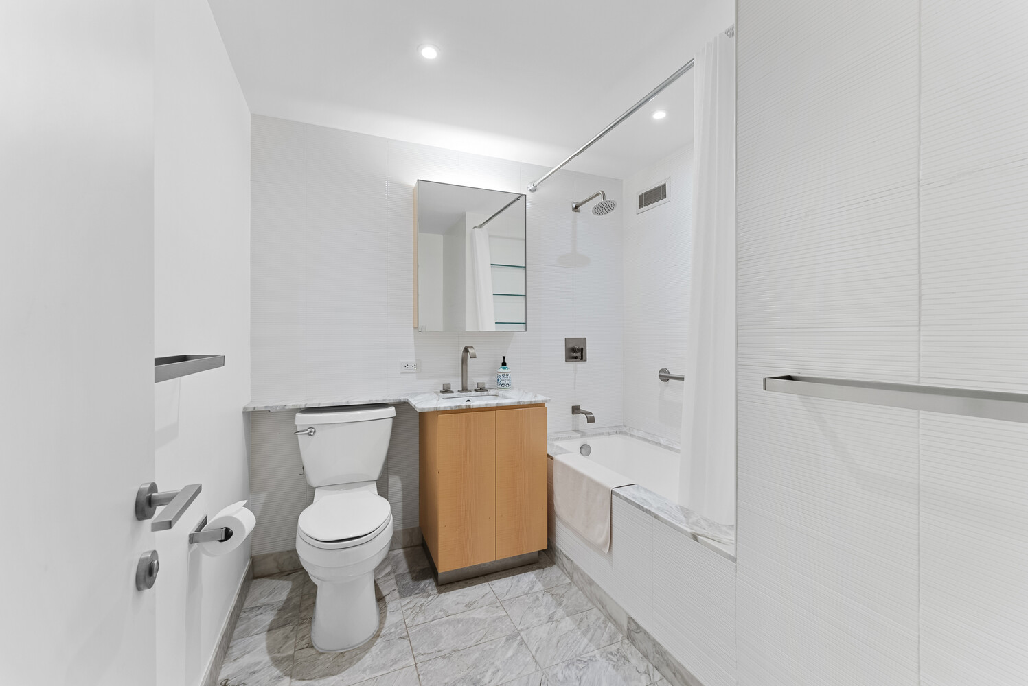 322 West 57th Street, Unit 39K Manhattan, NY 10019 - Photo 12 of 23 a white toilet sitting next to a bathroom sink and a shower