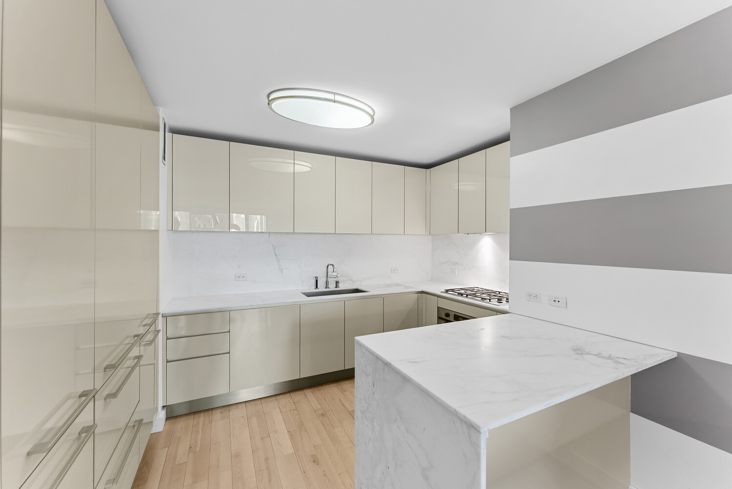 322 West 57th Street, Unit 39K Manhattan, NY 10019 - Photo 16 of 23 a kitchen with stainless steel appliances a sink a stove and white cabinets with wooden floor