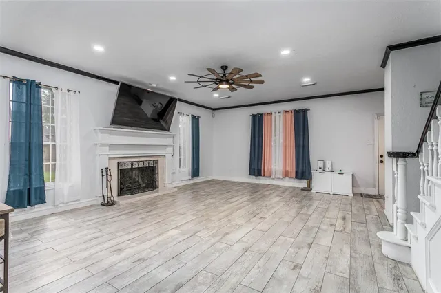 a view of an empty room with wooden floor and a fireplace