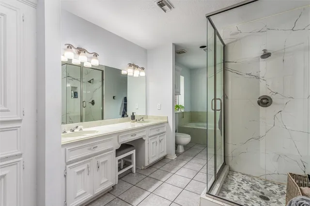 a spacious bathroom with a double vanity sink toilet and shower