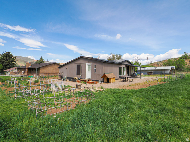 94 Spring Canyon Road Coalville, UT 84017 - Photo 5 of 50 Expansive backyard featuring a large green space, fenced garden beds, and an extended gravel patio