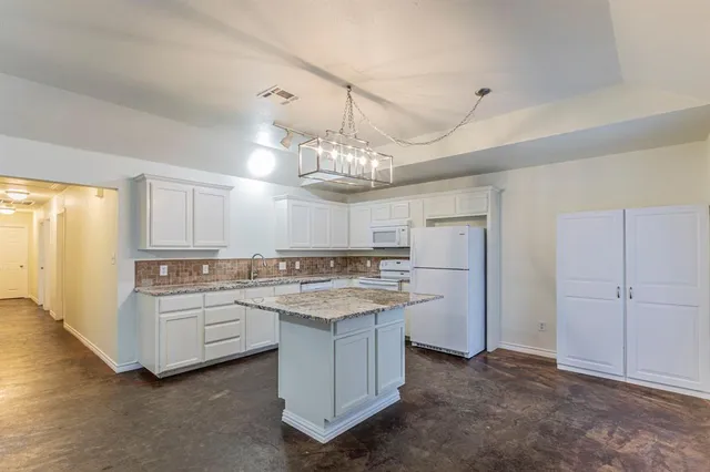 a kitchen that has a lot of white cabinets and stainless steel appliances