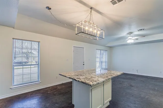 a view of kitchen with granite countertop cabinets and chandelier
