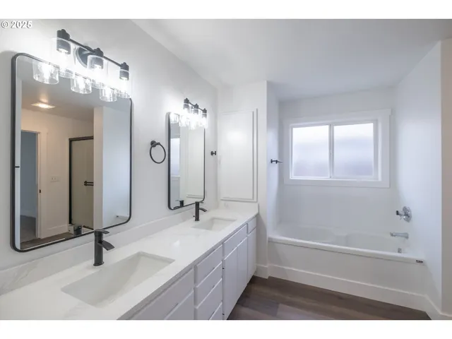 a bathroom with a double vanity sink a mirror and a bathtub