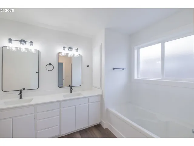 a bathroom with a double vanity sink a mirror and a bathtub
