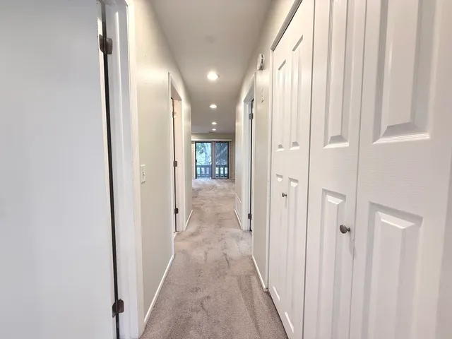 a view of a hallway with wooden floor and a bathroom