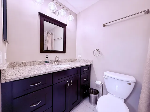 a bathroom with a granite countertop toilet sink and mirror