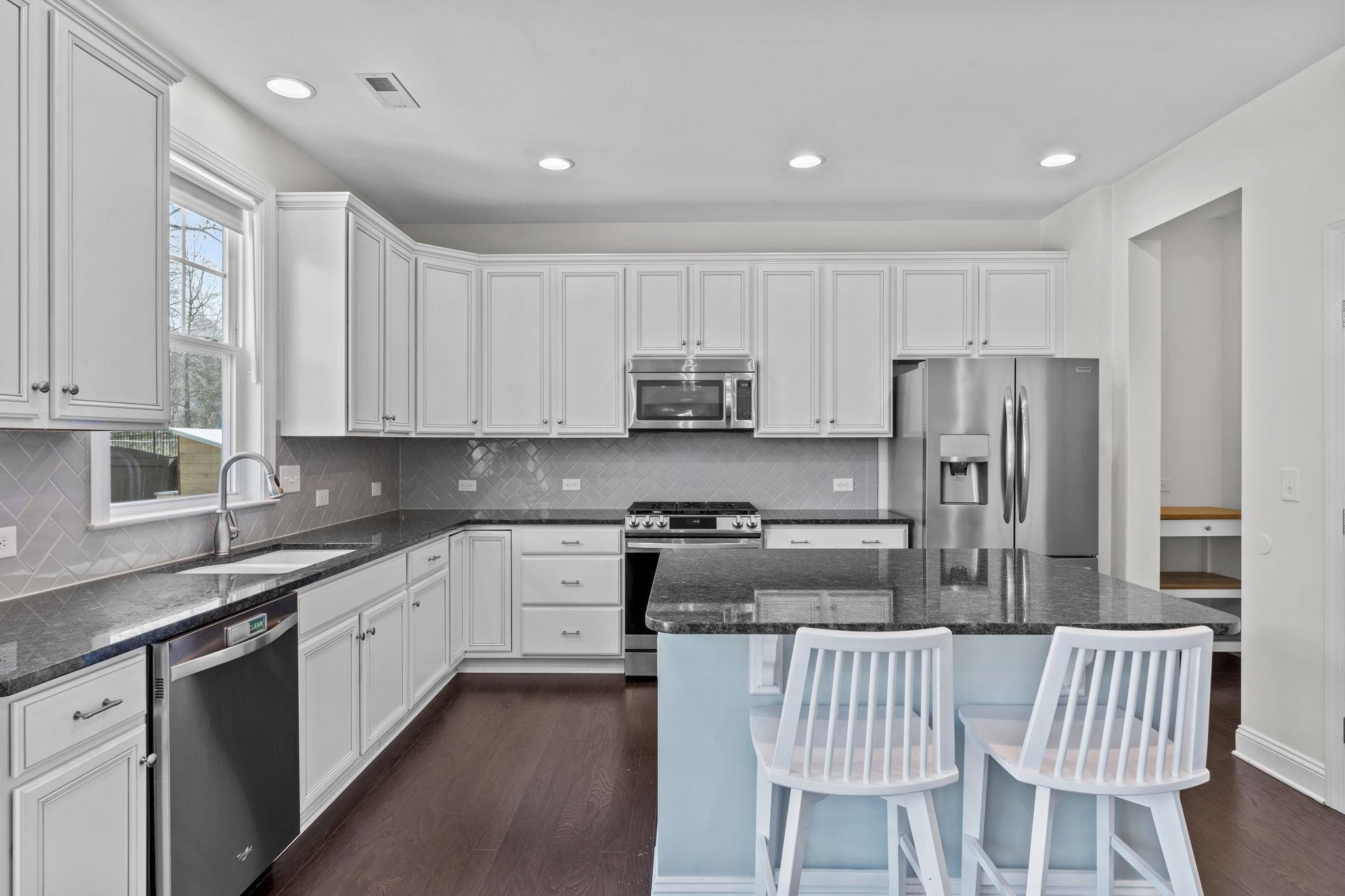 148 Morgan Ridge Road Holly Springs, NC 27540 - Photo 12 of 31 Timeless White Kitchen with Center Island Showcasing Granite Countertops and Pantry