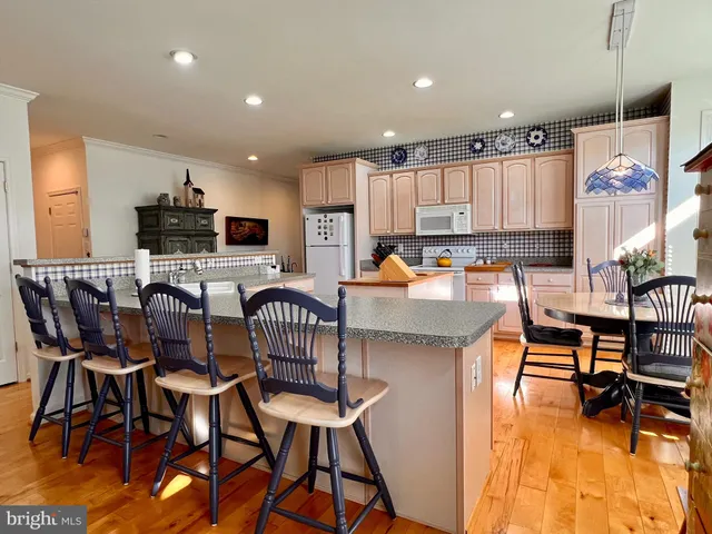 a kitchen with stainless steel appliances kitchen island granite countertop a dining table chairs stove a sink and a microwave