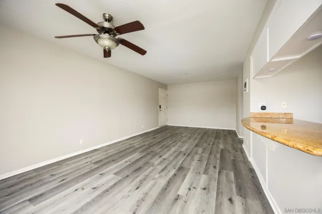 an empty room with a ceiling fan and wooden floor