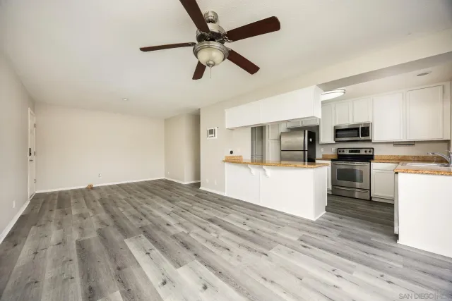 a view of kitchen with microwave a stove and white cabinets