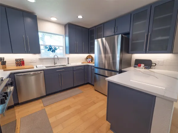 a kitchen with kitchen island granite countertop a sink cabinets and stainless steel appliances