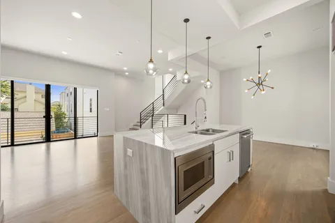 a spacious kitchen with stainless steel appliances granite countertop a stove and a chandelier