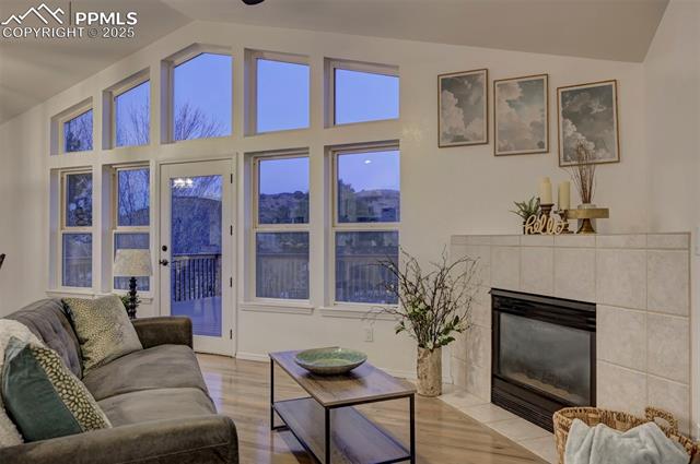 7790 Julynn Road Colorado Springs, CO 80919 - Photo 11 of 50 The Great Room has a vaulted ceiling, hardwood floors, a gas fireplace with tile surround, and wall of windows with views of the backyard.