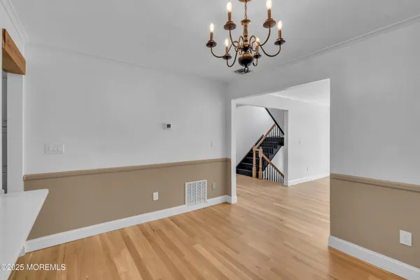a view of an empty room with wooden floor and stairs