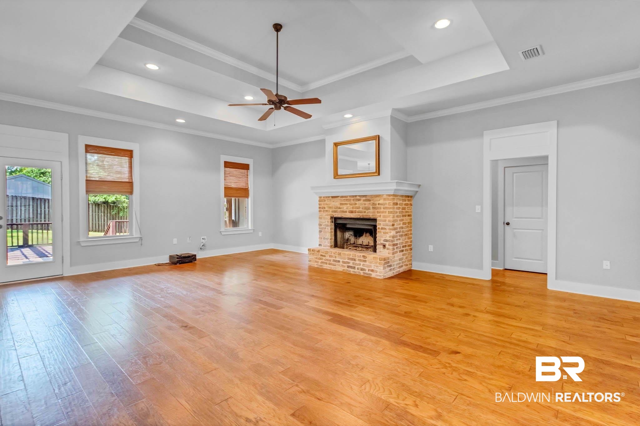 7854 Raegan Lane Daphne, AL 36527 - Photo 13 of 70 Living room featuring a tray ceiling, light wood-style floors, a fireplace, ceiling fan, and crown molding