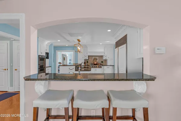 a kitchen with stainless steel appliances granite countertop a dining table chairs and a refrigerator