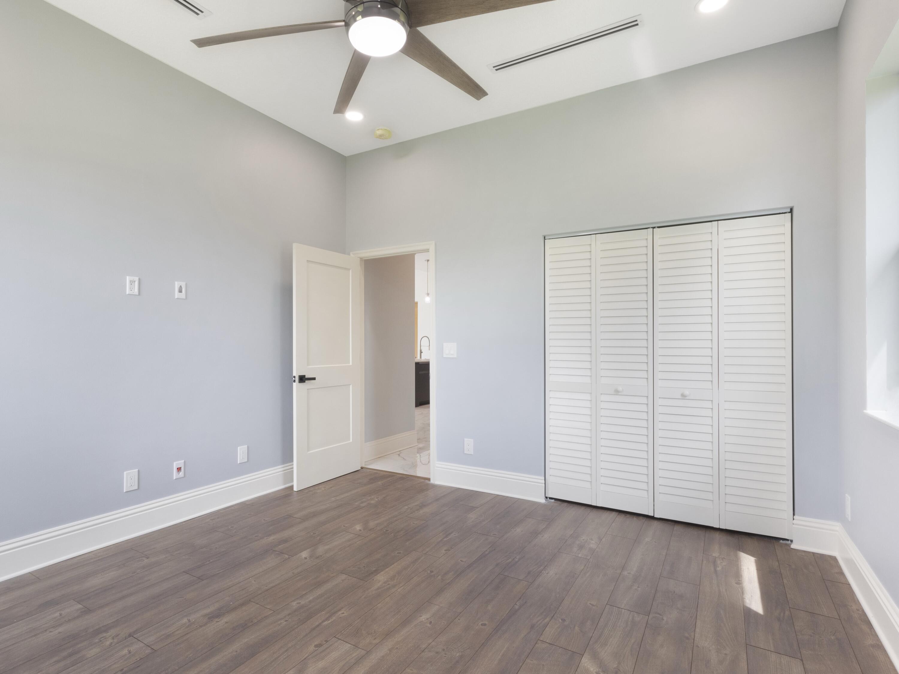 17436 71st Lane North Loxahatchee, FL 33470 - Photo 42 of 50 an empty room with wooden floor chandelier fan and entryway