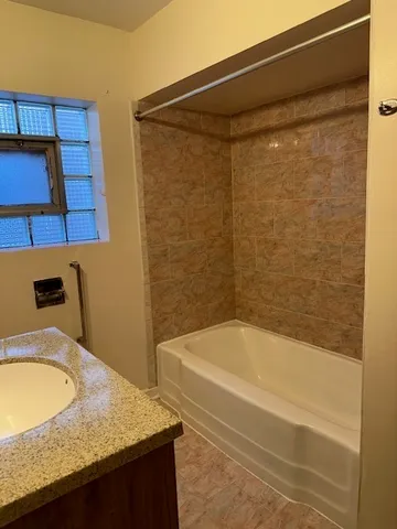 a bathroom with a granite countertop sink and bathtub
