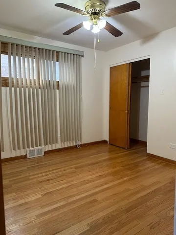 an empty room with wooden floor fan and windows