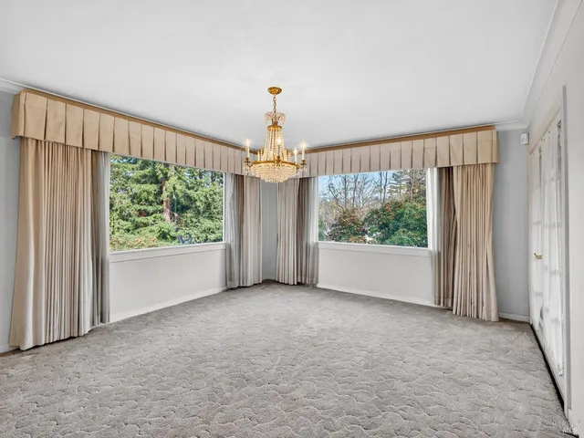 a view of a big room with windows and chandelier fan