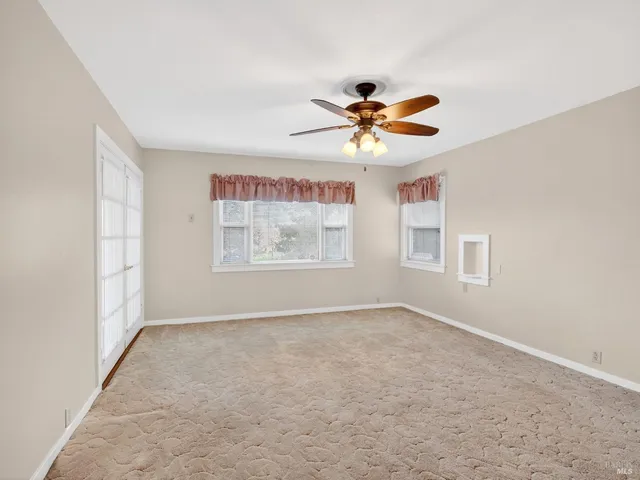 an empty room with windows and fan