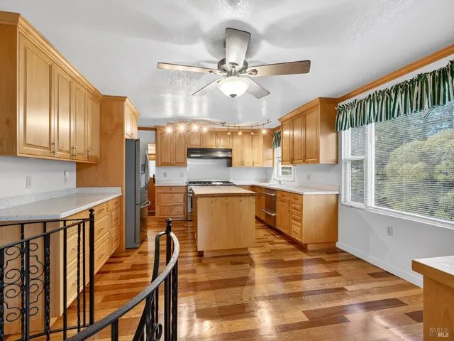 a kitchen with stainless steel appliances kitchen island granite countertop a table chairs in it and wooden floors