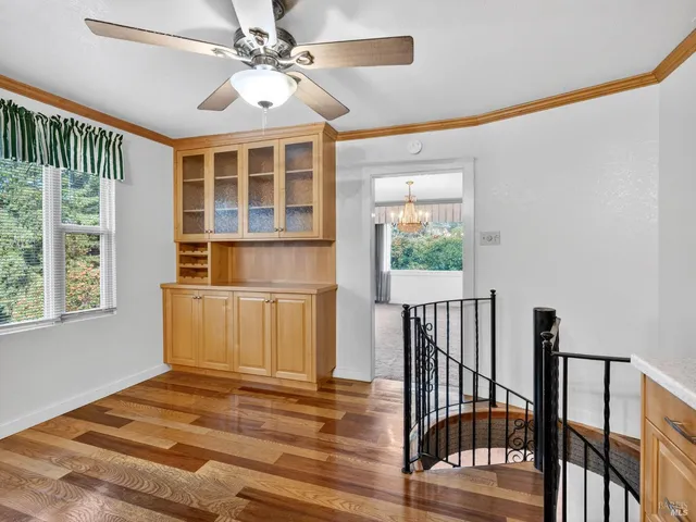 a view of a bedroom with wooden floor and a ceiling fan
