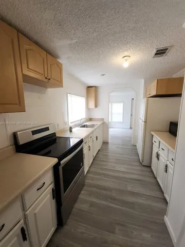 a kitchen with cabinets wooden floor and stainless steel appliances