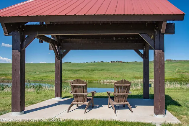 a view of chairs and table in the patio next to a yard