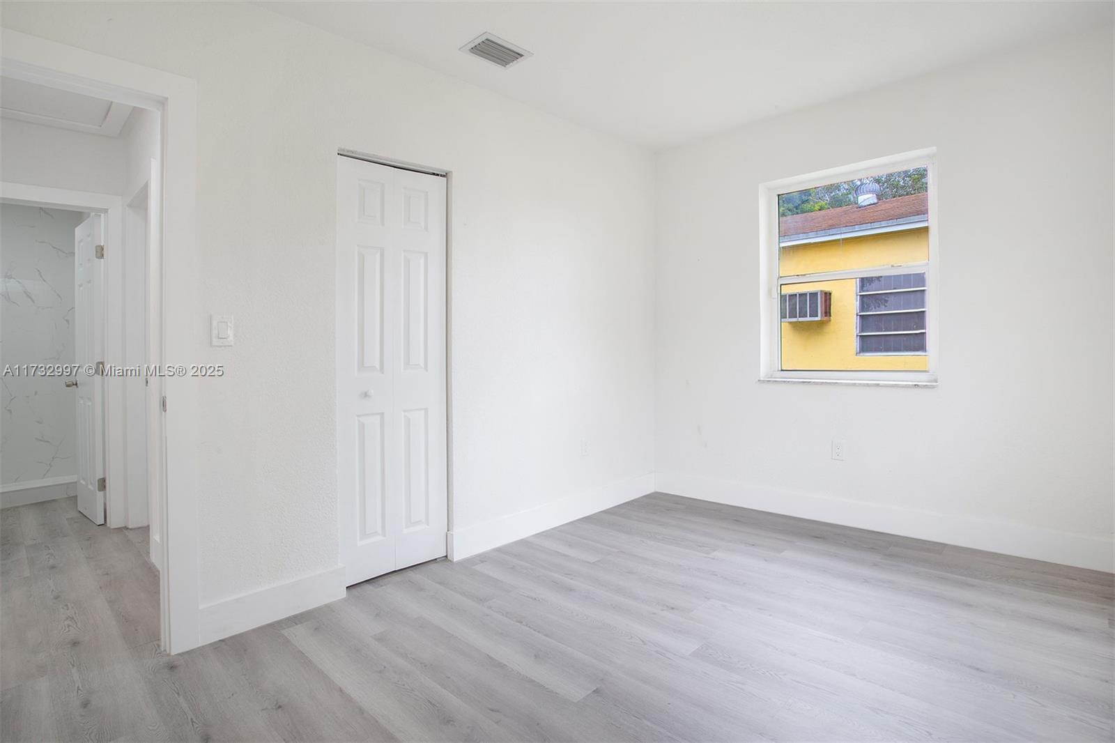 1923 Northwest 66th Street Miami, FL 33147 - Photo 20 of 29 a view of an empty room with wooden floor and a window