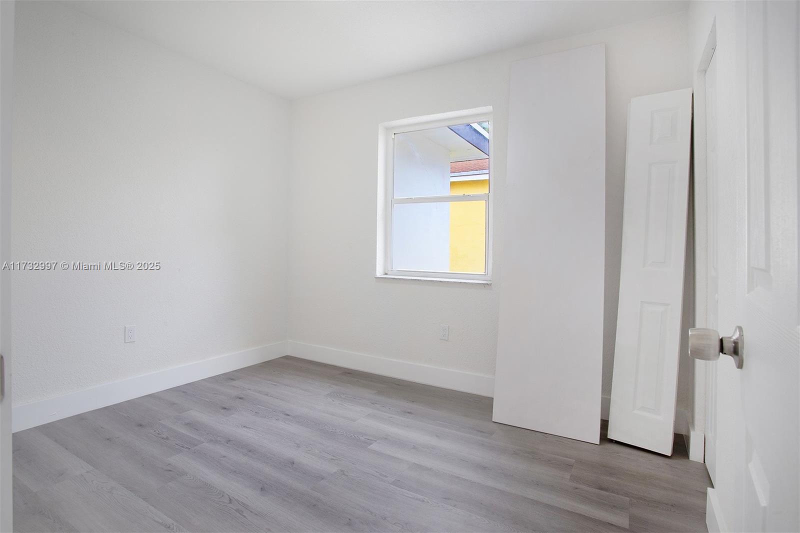 1923 Northwest 66th Street Miami, FL 33147 - Photo 21 of 29 an empty room with a window and wooden floor