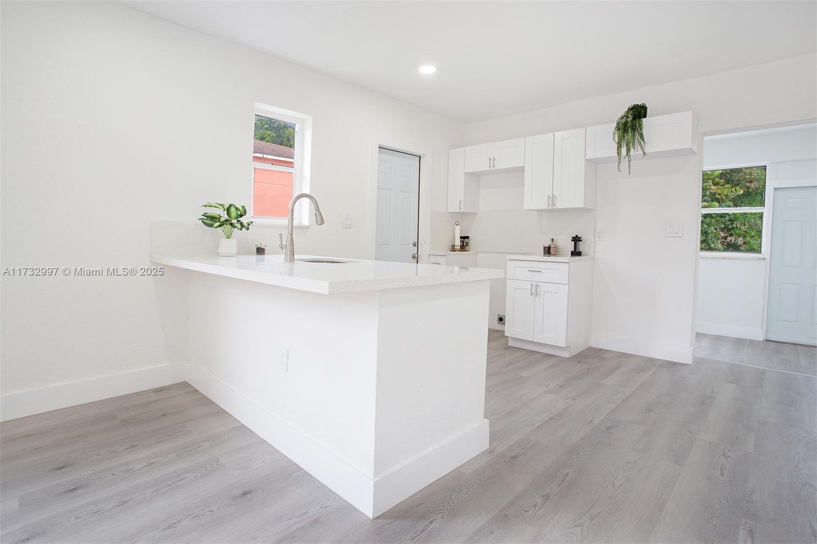 1923 Northwest 66th Street Miami, FL 33147 - Photo 6 of 29 a kitchen with white cabinets and wooden floor