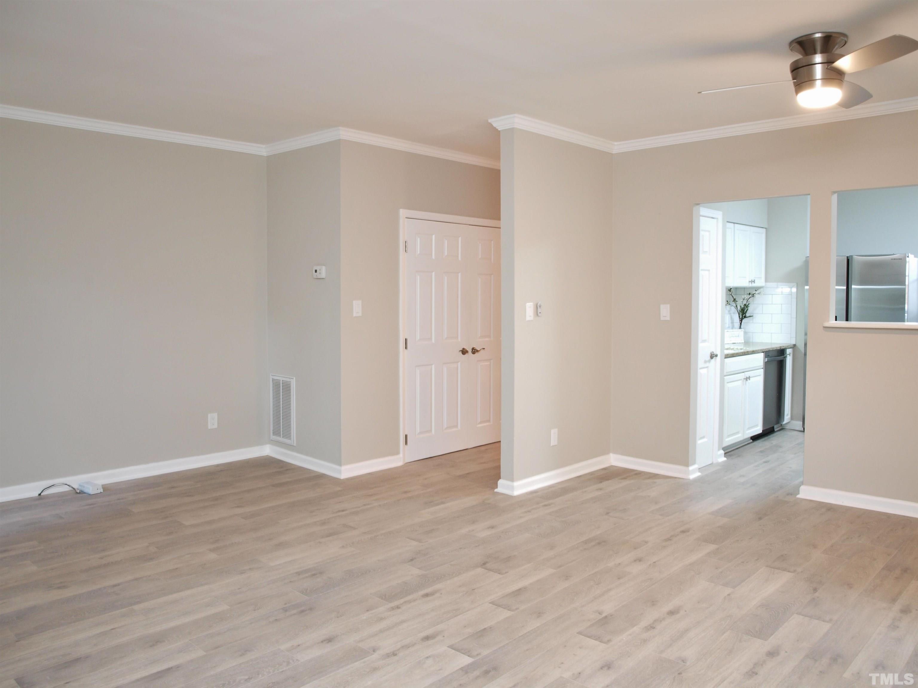 6123 Bushmills Street Raleigh, NC 27613 - Photo 4 of 16 a view of empty room with wooden floor and kitchen view