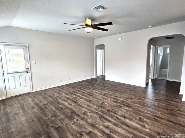 an empty room with wooden floor and windows
