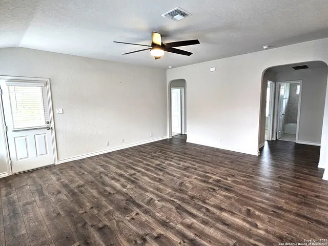 an empty room with wooden floor and windows