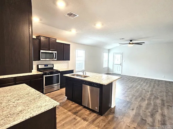 a kitchen with kitchen island granite countertop a sink stove and refrigerator