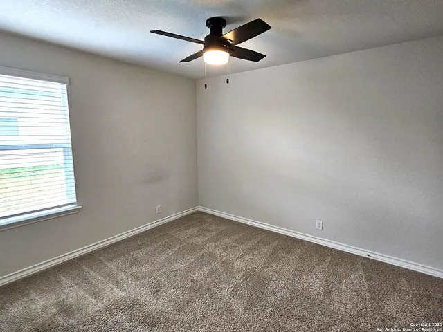 an empty room with a window and a fan