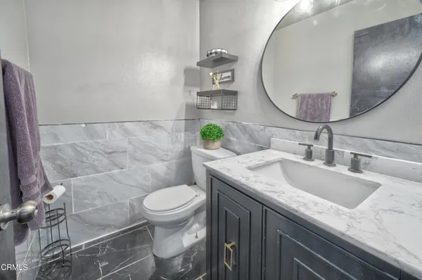 a bathroom with a granite countertop toilet sink and mirror