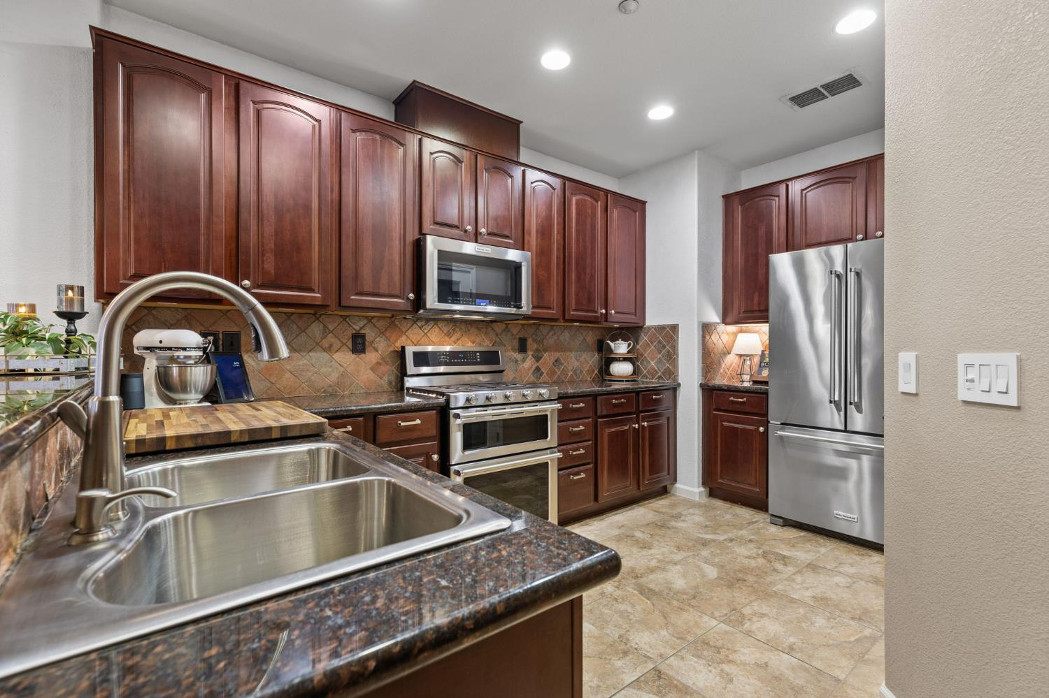 1107 Hudson Circle Lincoln, CA 95648 - Photo 16 of 51 Updated kitchen features a split stainless steel sink with a pull-out faucet and granite counters