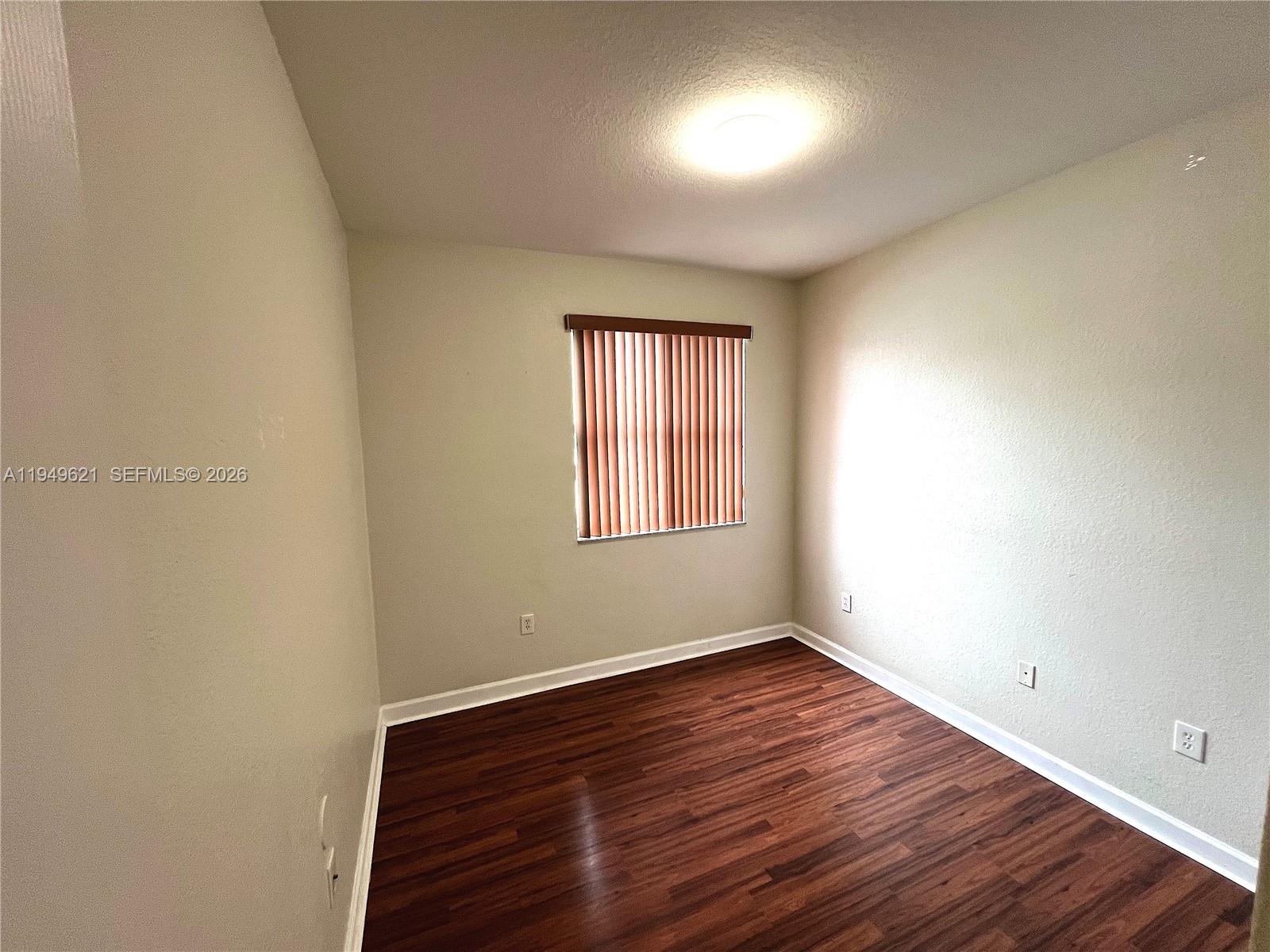 1660 Southeast 29th Street, Unit 101 Homestead, FL 33035 - Photo 14 of 18 wooden floor in an empty room with a window
