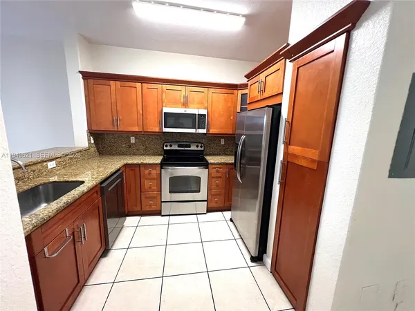 a kitchen with stainless steel appliances granite countertop a refrigerator a stove a sink and a window