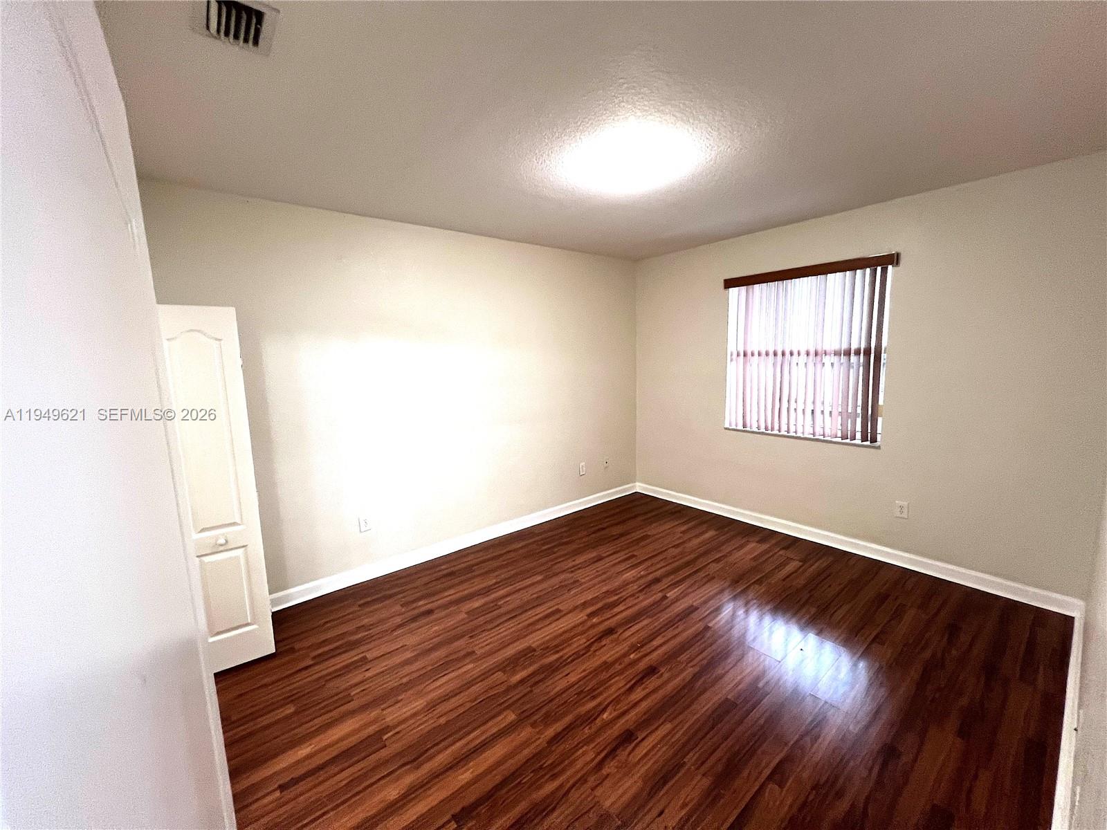 1660 Southeast 29th Street, Unit 101 Homestead, FL 33035 - Photo 8 of 18 an empty room with wooden floor and windows