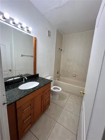 a bathroom with a granite countertop sink a toilet a mirror and shower