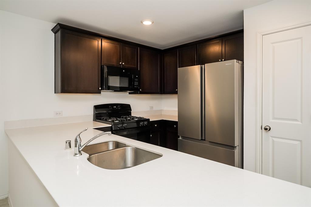 14841 Firerock Road Haslet, TX 76052 - Photo 9 of 18 a kitchen with a refrigerator and a sink